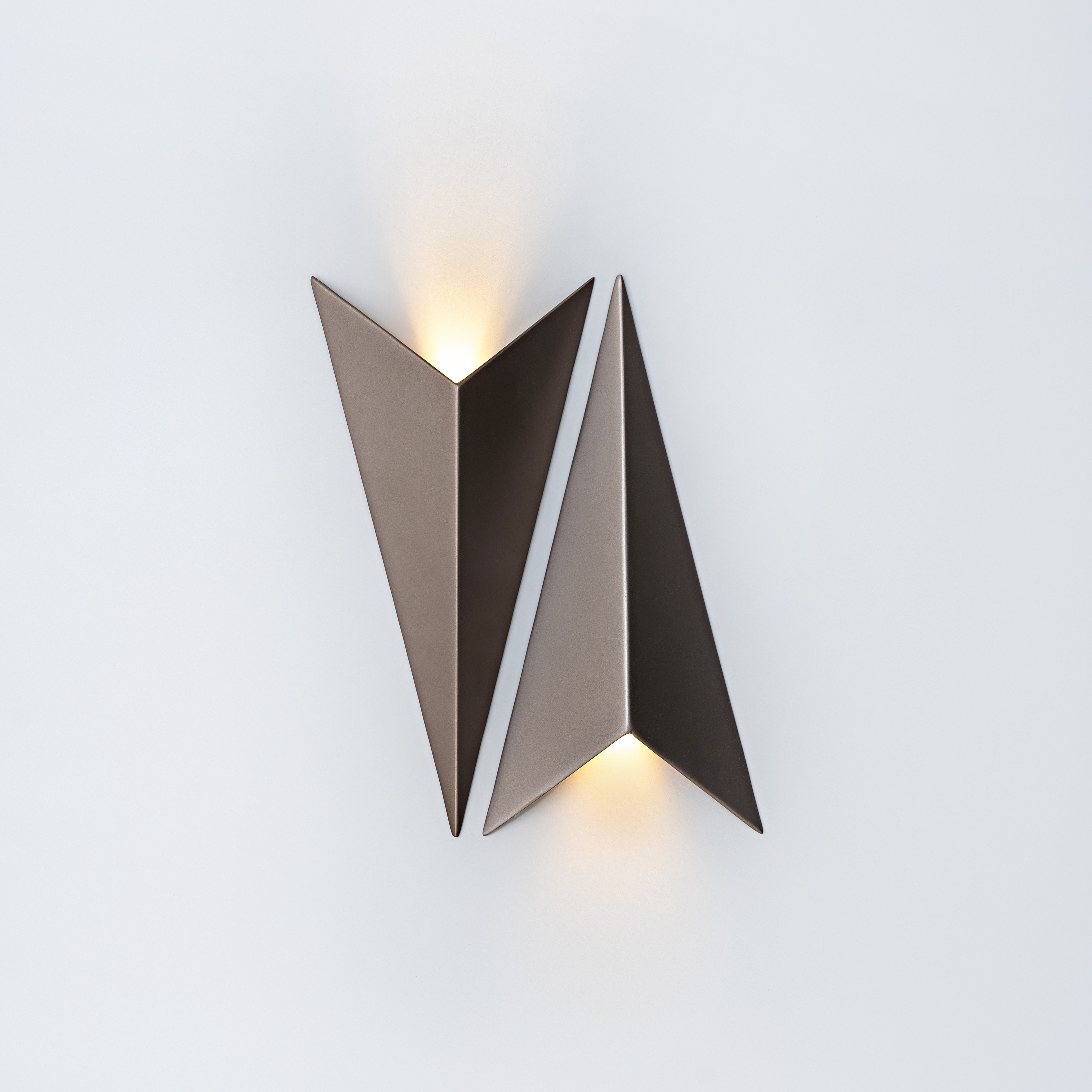 Arandela de LED triangular Avio da Bella Itália instalada na parede, com design moderno, luz indireta e acabamento sofisticado, ideal para cabeceira de cama e lavabos.